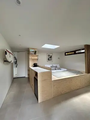 a bedroom with a large bed and a kitchen at Tiny house by the beach in Noordwijk aan Zee