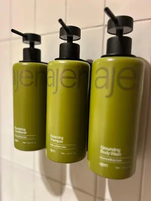 a group of three green shampoo bottles on a wall at Tiny house by the beach in Noordwijk aan Zee