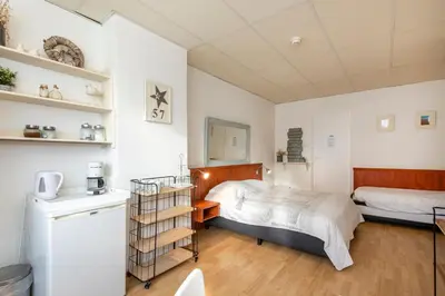 a small bedroom with a bed and a kitchen at Blankebil Rooms in Zandvoort