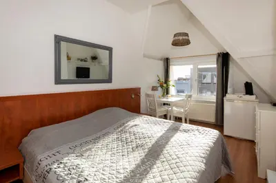 a bedroom with a bed and a mirror and a table at Blankebil Rooms in Zandvoort