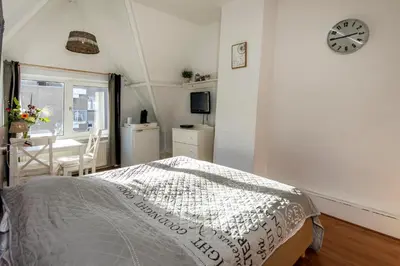 a bedroom with a bed and a clock on the wall at Blankebil Rooms in Zandvoort