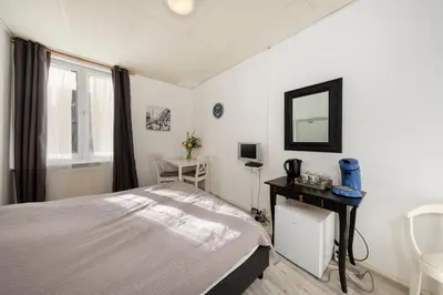 a bedroom with a bed and a mirror and a window at Blankebil Rooms in Zandvoort
