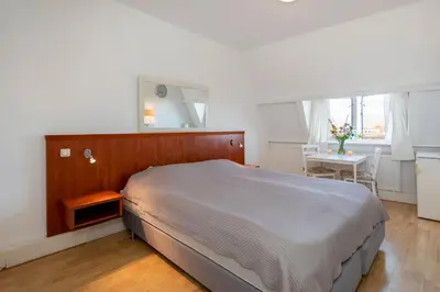 a bedroom with a large bed and a table at Blankebil Rooms in Zandvoort