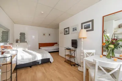 a bedroom with a bed and a table and a tv at Blankebil Rooms in Zandvoort
