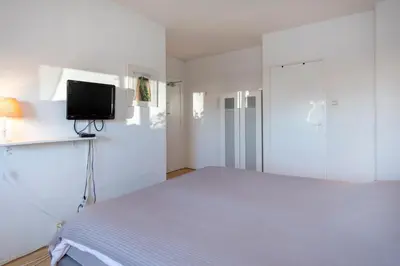 a bedroom with a bed and a tv on a wall at Blankebil Rooms in Zandvoort