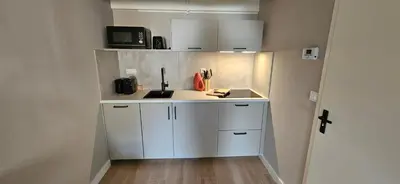 a small kitchen with white cabinets and a microwave at Bulbs & Beach in Noordwijk