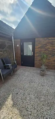 a patio with a black door and a chair and a plant at Bulbs & Beach in Noordwijk