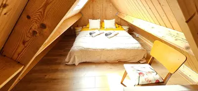 a small attic bedroom with a bed and a chair at Bulbs & Beach in Noordwijk
