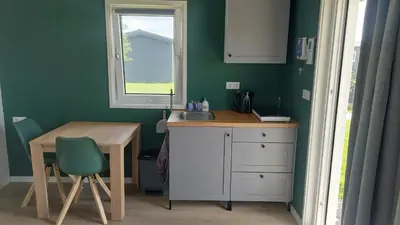a kitchen with a sink and a table and a window at Recreatie aan de Vecht, Hooibergje 3, Weesp in Weesp