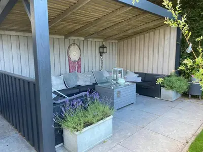 a pergola with a couch on a patio at Ruime woning met jacuzzi, 10 min van strand in Lisse