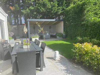 a patio with a table and chairs in a yard at Ruime woning met jacuzzi, 10 min van strand in Lisse