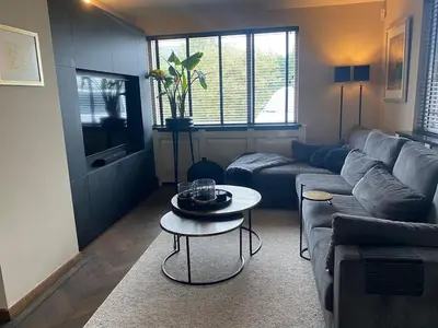 a living room with a couch and a table at Ruime woning met jacuzzi, 10 min van strand in Lisse