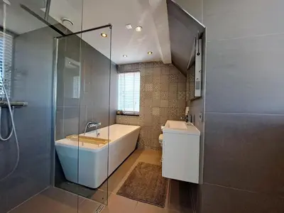 a bathroom with a tub and a sink and a shower at Ruime woning met jacuzzi, 10 min van strand in Lisse