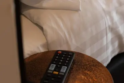 a remote control sitting on a table next to a bed at Midtown Hotel triple in Amsterdam