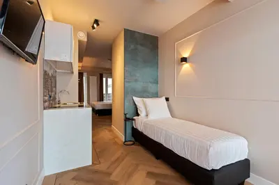 a small bedroom with a bed and a television at Midtown Hotel triple in Amsterdam
