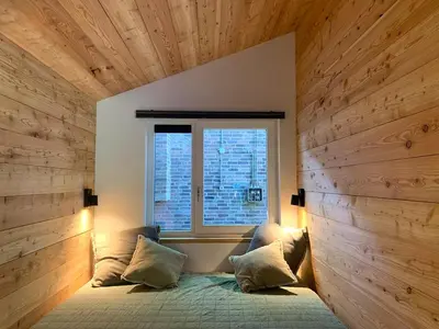a bedroom with a bed with a wooden wall at Behouden Huis in Ons Belang