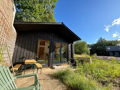 a small house with a green bench and a table at Behouden Huis in Ons Belang