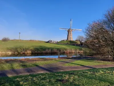 a windmill on a hill next to a river at Comfort Apartment Hoofddorp near Amsterdam Schiphol in Hoofddorp