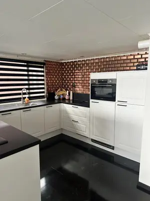 a kitchen with white cabinets and a brick wall at woonboot de dobber loosdrechtse plassen 4-8 personen in Loosdrecht