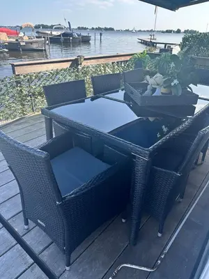 a table with chairs and an umbrella on a dock at woonboot de dobber loosdrechtse plassen 4-8 personen in Loosdrecht