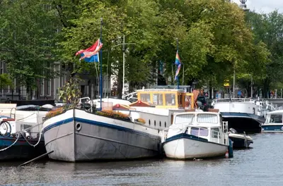 a group of boats docked in the water at art deco houseboat on super location in Amsterdam