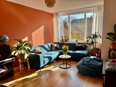a living room with a blue couch and a window at Family home in Haarlem with garden, near beach & Amsterdam in Haarlem