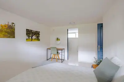 a white bedroom with a bed and a desk at Family home in Haarlem with garden, near beach & Amsterdam in Haarlem