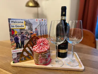 a bottle of wine and two glasses on a table at Gouda city center apartment with private garden and 2 bicycles in Gouda
