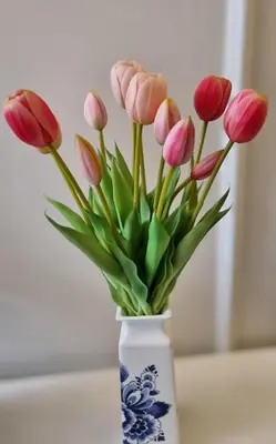 a white vase with pink flowers in it at Gouda city center apartment with private garden and 2 bicycles in Gouda