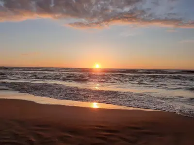 a sunset on a beach with the ocean at Studio 21 stylish and luxurious apartment in Noordwijk