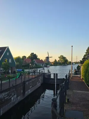 a water canal with a windmill in the background at Ossestal in Assendelft