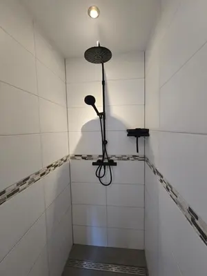 a walk in shower with a light on the wall at Ossestal in Assendelft