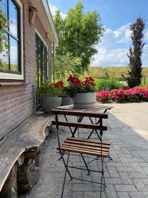 a wooden bench sitting next to a building with flowers at Bij De Neckermolen- Bed and Stay Beemster in Zuidoostbeemster