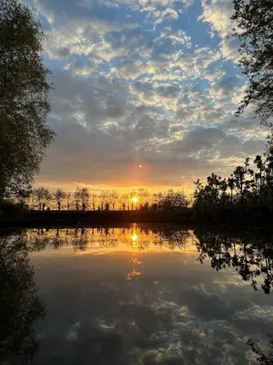 a sunset over a lake with the reflection of the sky at Bij De Neckermolen- Bed and Stay Beemster in Zuidoostbeemster