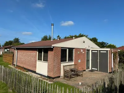 a brick house with a bench and a fence at Rekerlanden 218 by ZILT in Warmenhuizen