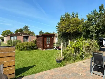 a yard with a fence and a house at Rekerlanden 218 by ZILT in Warmenhuizen