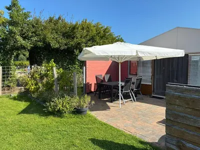 a patio with an umbrella and a table and chairs at Rekerlanden 218 by ZILT in Warmenhuizen