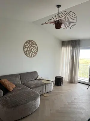 a living room with a couch and a large window at Blvd 79 in Katwijk aan Zee