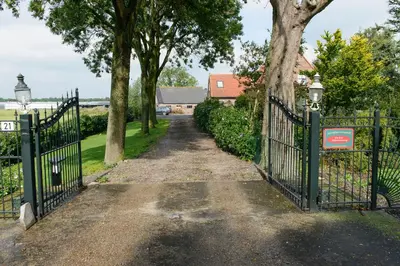 a gate leading to a driveway with trees at Buitenplaats Langewijk in Zuidoostbeemster