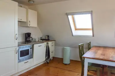 a kitchen with white cabinets and a table and a window at Buitenplaats Langewijk in Zuidoostbeemster