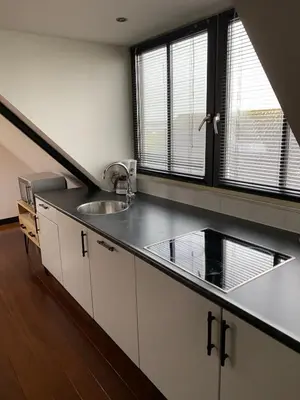 a kitchen with white cabinets and a sink and two windows at Buitenplaats Langewijk in Zuidoostbeemster