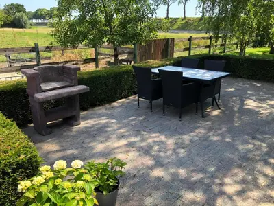 a table and chairs on a patio with a bench at Buitenplaats Langewijk in Zuidoostbeemster