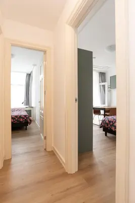 a room with a hallway with two beds and a table at Central HotSpot Apartment in Amsterdam