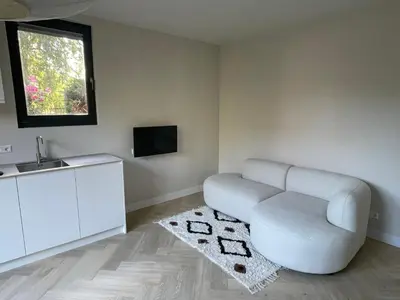 a living room with a white chair and a sink at Haarlems Huisje in Haarlem