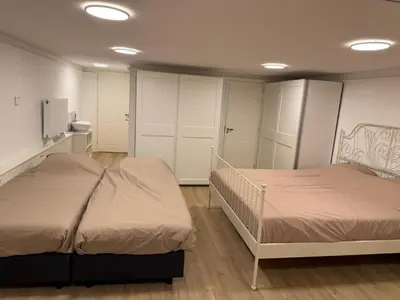 two beds in a room with white cabinets at Herengracht 204 Souterrain Studio Apt without kitchen in Amsterdam