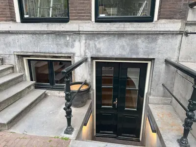 a building with a black door and two windows at Herengracht 204 Souterrain Studio Apt without kitchen in Amsterdam