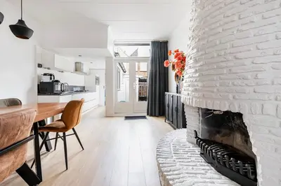 a living room with a fireplace and a dining room table at The Alkmaar Family House in Alkmaar