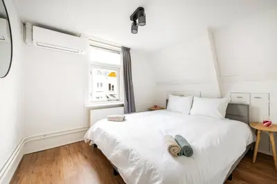 a bedroom with a large white bed with a window at The Alkmaar Family House in Alkmaar