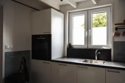 a kitchen with white cabinets and a sink and a window at Another day in paradise in Tuitjenhorn