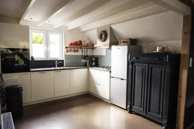 a kitchen with white cabinets and a black refrigerator at Another day in paradise in Tuitjenhorn